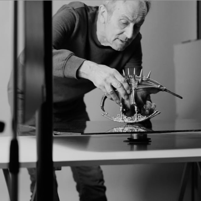 Mann arrangiert ein Modell eines Drachen auf einem Tisch in einem Studio.